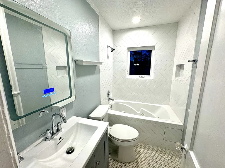 Bathroom with new tile, LED mirror and Bluetooth speaker, dimmable lighting and a new rollout casement window.