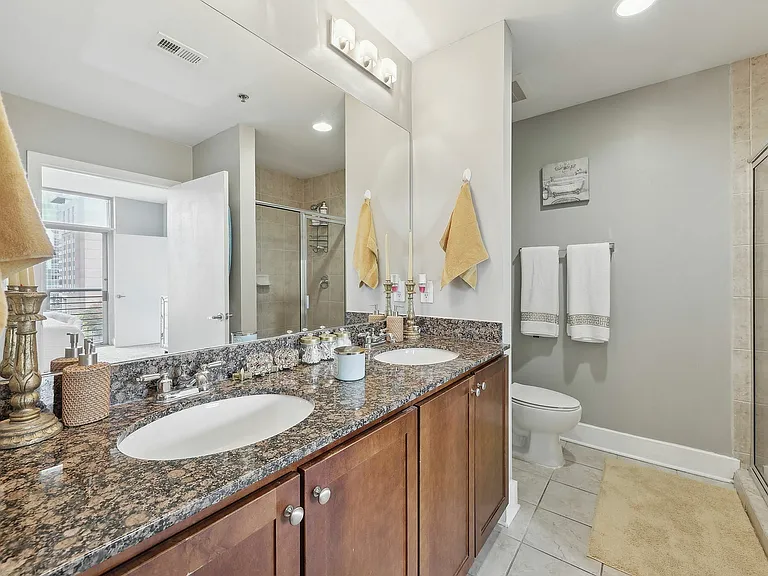 Spacious bathroom featuring double vanity, granite countertops, and walk-in glass shower
