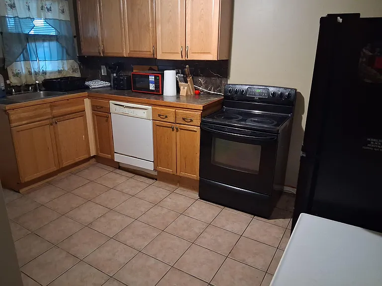Functional kitchen with ample wood cabinetry, generous counter space, and full-size stove, dishwasher, and refrigerator.