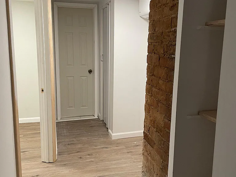 Hallway from master bedroom. New flooring, built in bookcase, exposed brick. Separate split for AC/Heat. And room for office space in front of window. Left door is 2nd bedroom. Has extra closet and ends in entrance to upstairs bathroom