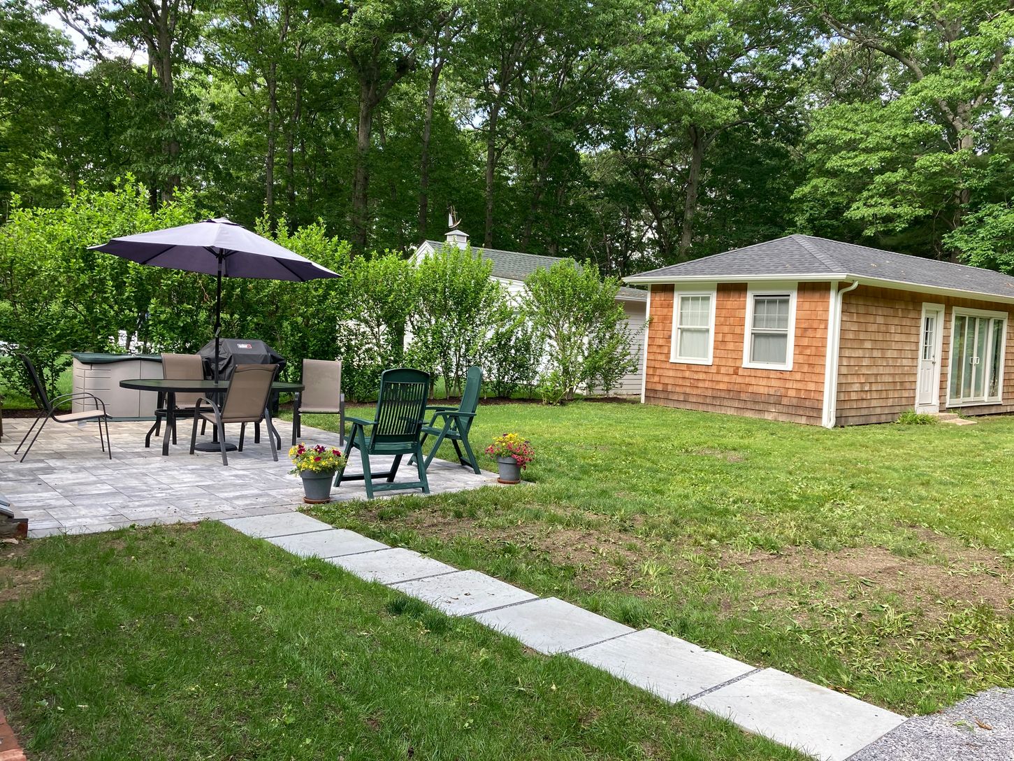  back patio equipped with a weber gas grill, outdoor dining table and chairs and patio umbrella.