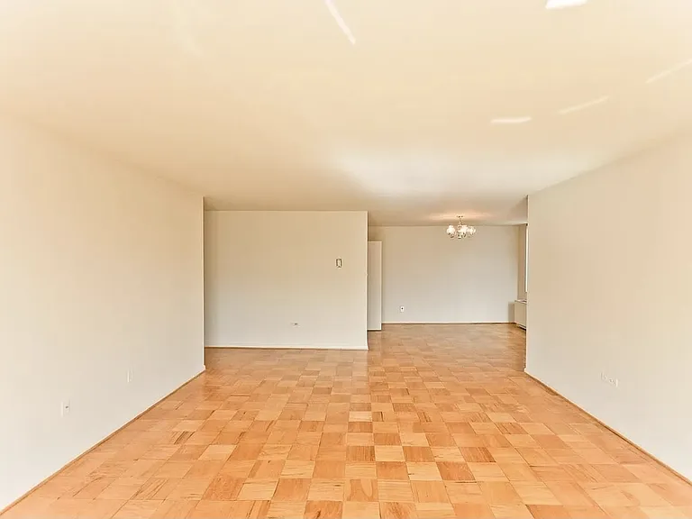 View of the living room from the balcony doors. Enclosed kitchen on the left, dining room nook on the right.