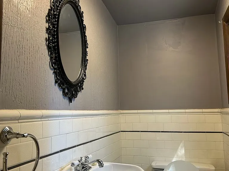 Guest half-bath - marble flooring and tiled walls - just off the 1st floor living room. Modern light fixture.