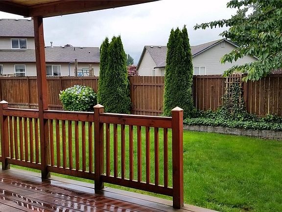 Backyard view of gate to common area between two trees.
