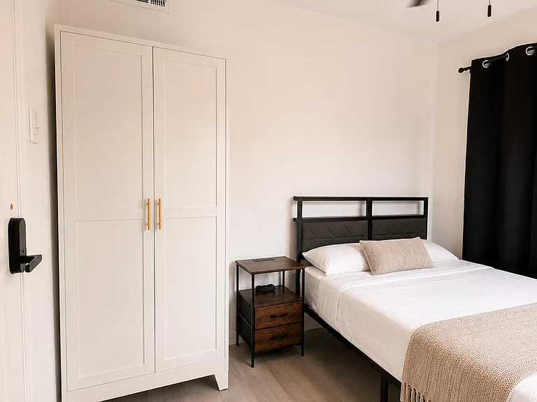 Furnished bedroom with a full bed, nightstand, and wardrobe closet, plus a ceiling fan for year-round comfort.