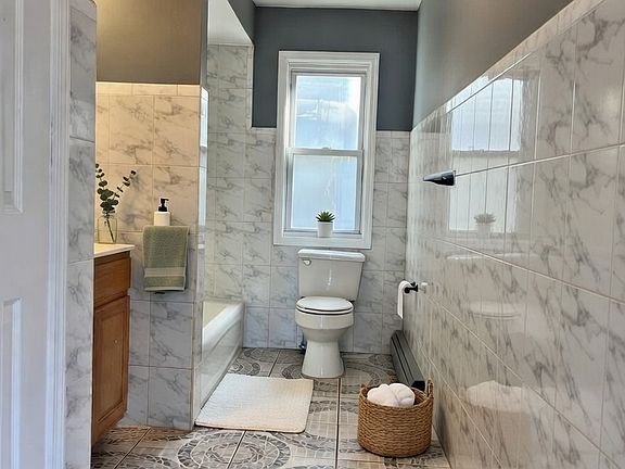 Spacious main bathroom with a linen closet and window allowing sunlight in