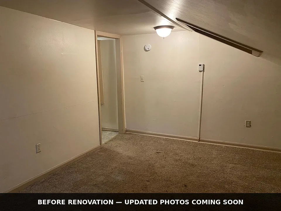 Separate bedroom with distinctive sloped ceiling and skylight. BEFORE renovation _ carpet is being replaced with new LVP flooring and the room freshly painted.