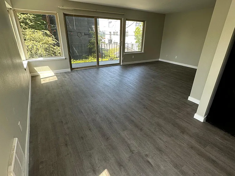 Large living room with balcony and dining room area. West facing balcony and windows and south facing windows in the living and dining area.