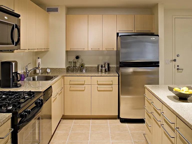 Classic Package I kitchen with beige speckled countertops, beige cabinets, stainless steel appliances, and hard surface flooring