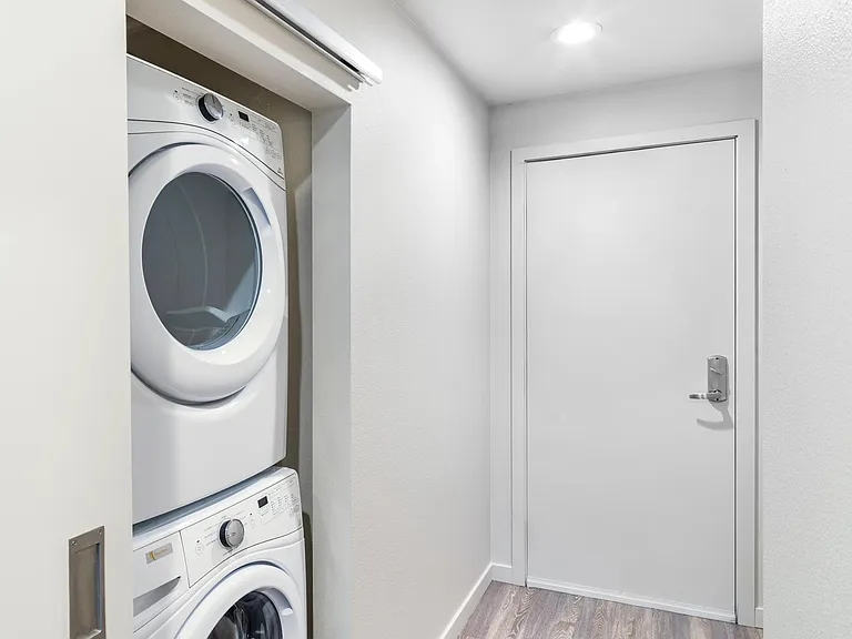 A neatly tucked in-home laundry area with a stacked washer and dryer, offering a streamlined setup that keeps daily tasks simple and out of the way.