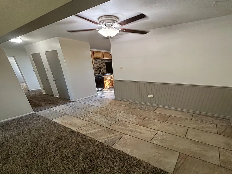 Inviting living area with plush carpet, leading to a cozy dining space and modern kitchen.