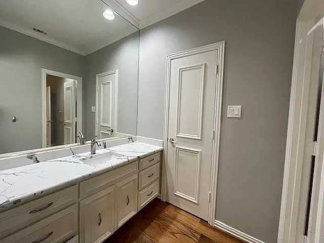 Bathroom featuring vanity, dark wood-style floors, crown molding, and recessed lighting