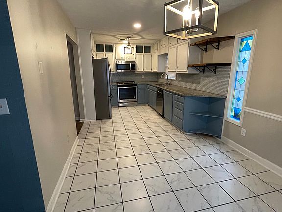 Newly renovated kitchen and breakfast nook with new appliances, gas stovetop and oven, and butcher block shelves.