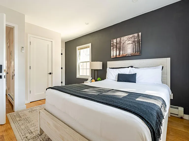 Well-appointed bedroom featuring a full bed, bedside table with lamp, and a window for natural light.