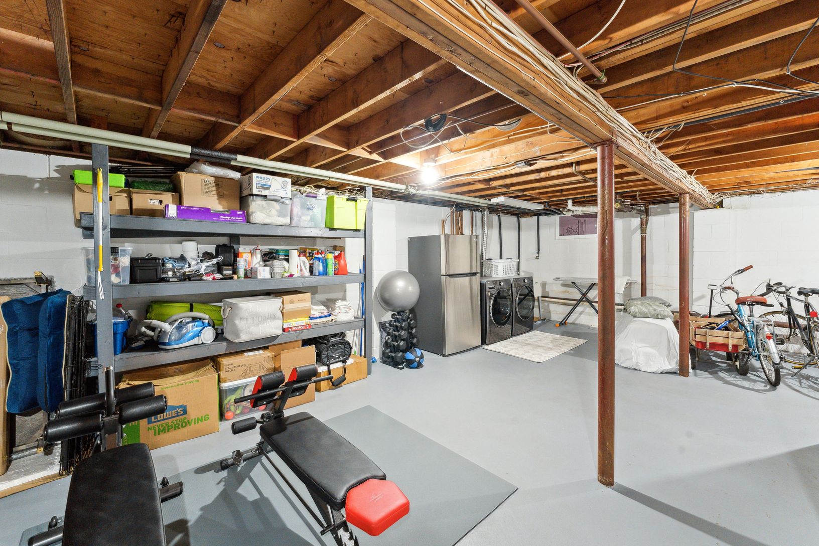 laundry, exercise equipment, bikes and beach wagon in basement/garage
