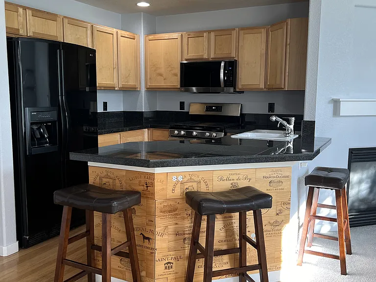 Kitchen with granite tile countertops and maple cabinetry. Stainless/black appliances.
