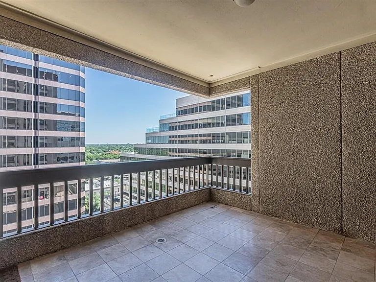 Private balcony featuring tiled flooring, a sturdy railing, textured wall finishes, and expansive urban scenery