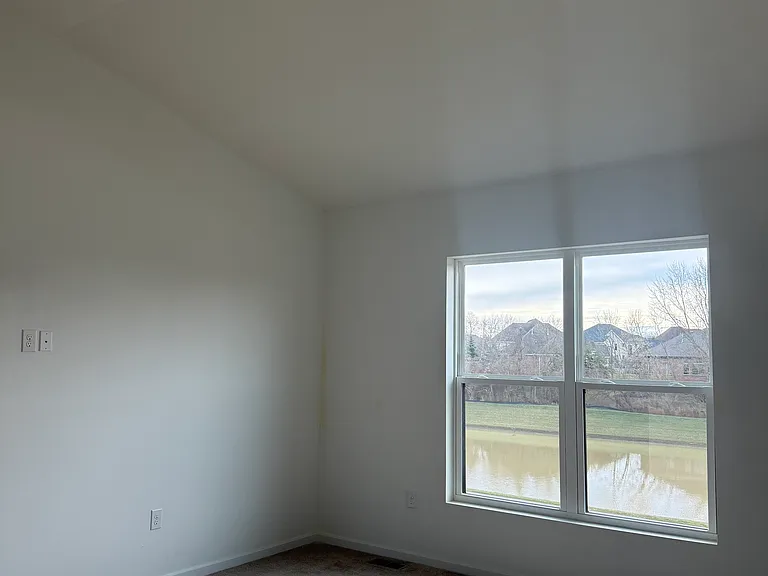 Spacious Master bedroom overlooks pond & features vaulted ceiling. Blackout blinds installed (not shown in picture).