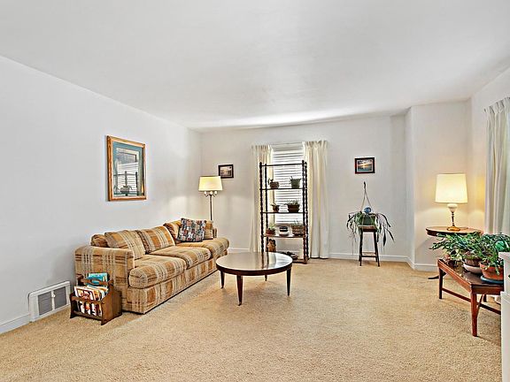 Carpeting covers the hardwood floor  in the living room and windows let in so much natural light