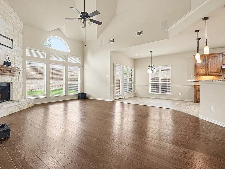 Spacious living area featuring high vaulted ceilings, wood-finish flooring, and an expansive window wall with an arched transom