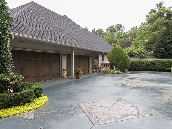 Stained driveway with accents leads to four-car garage