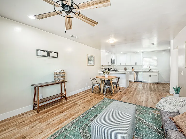 Living Room is fully Furnished with Sofas, Area Rug, Dining Table, Scenic Arts on the Wall and Decor Tables.