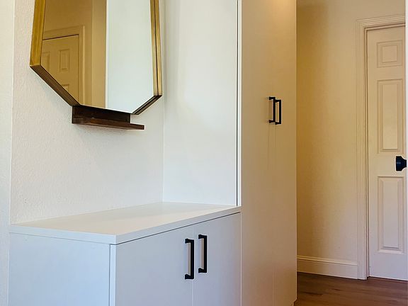 Unit hallway near the entry with built in cabinets and vanity mirror