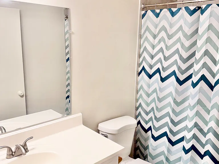 Full bathroom with single-sink vanity, mirrored cabinet storage, and a tub/shower combo with tile surround.