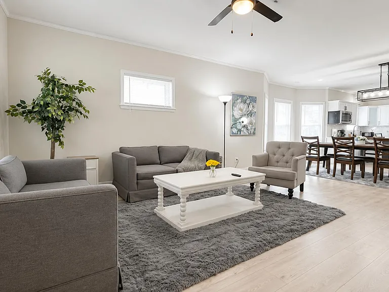 Open-concept living area with comfortable seating, ceiling fan, and easy flow to the dining space and full kitchen.