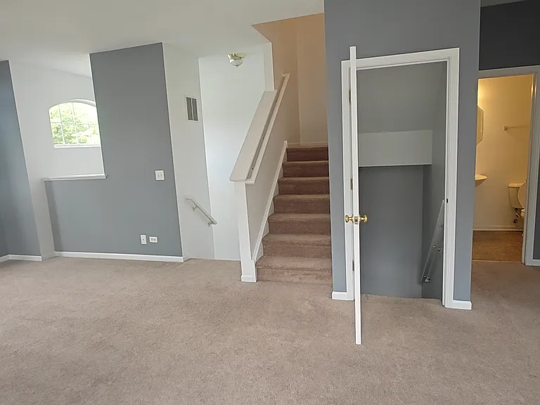 In the living room with view to half bath, staircase to garage, and upstairs staircase
