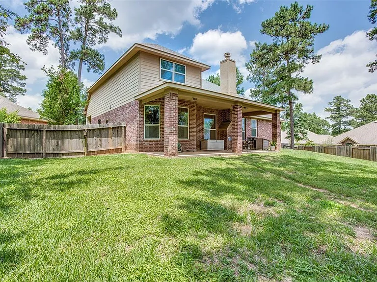 Spacious fenced backyard with a covered patio for outdoor dining and lounging, plus mature trees for shade and privacy.