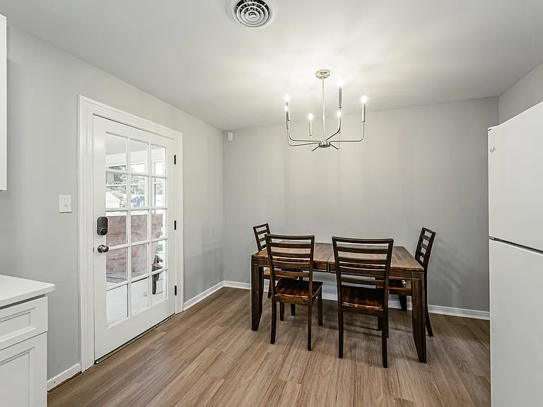 Dedicated dining area with table seating, updated flooring, and a glass-panel door providing easy outdoor access.