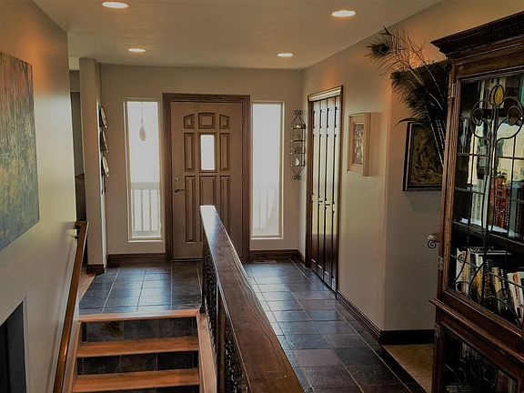 Entryway. Stairs lead to garage and apartment. Dining and Kitchen to left and Guest Bedrooms with Laundry to right.