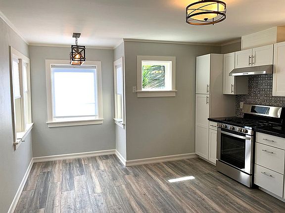 View of the spacious kitchen and dining area with fresh paint, new tile, fixtures, appliances, hardwood flooring, and cabinets.
