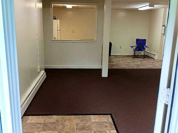 View looking into the apartment from the front door shows part of the living room and the dining area in the kitchen. The refrigerator is visible through the pass-through window from kitchen to living room.