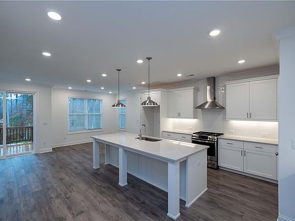 Kitchen featuring stainless steel gas range oven, pendant lighting, wall chimney range hood and ston