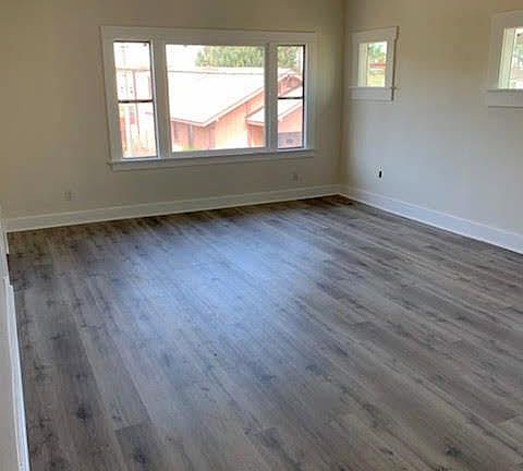 Huge living room with new wood flooring, new windows, and a fresh coat of paint. Lots of natural sunlight.