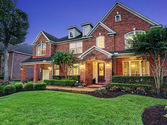 This home has gorgeous curb appeal by day or night. Lush landscaping surrounds this brick two-story home with a large covered porch and a porte cochere.