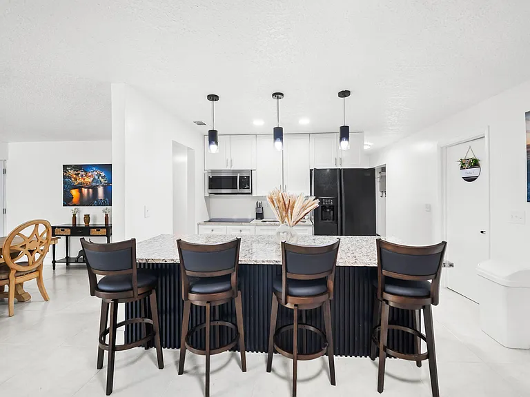 Open kitchen with a large stone island, bar seating, and stainless appliances, plus nearby dining space for easy meals.