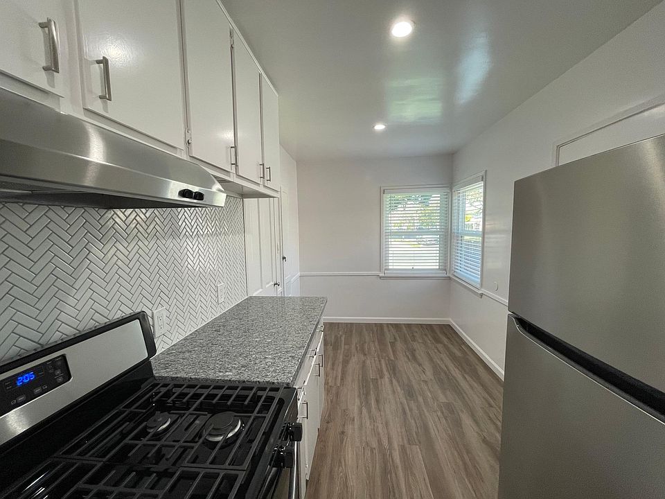 Remodeled kitchen with new granite countertops, new stove, exhaust fan, stainless steel refrigerator and space for dining table. Also, includes antique built-in small ironing board.