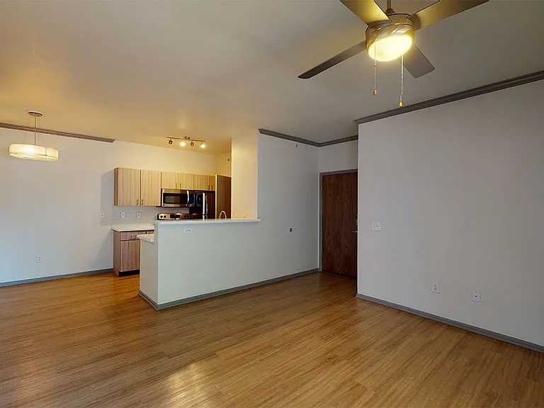 Gourmet kitchen with stainless steel appliances, dining and living room with wood-style flooring.