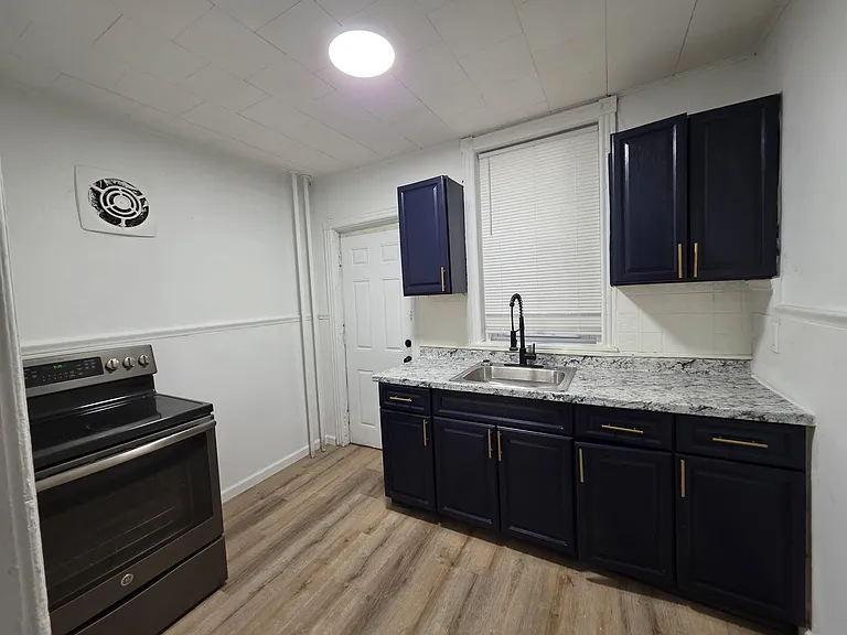 Updated kitchen with granite-look counters, stainless range, generous cabinet storage, and a deep sink under the window.