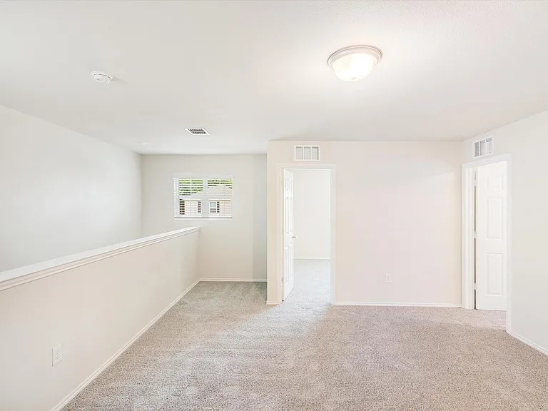 Carpeted upper-level landing featuring neutral paint, a ceiling-mounted light fixture, white trim, and a window with blinds