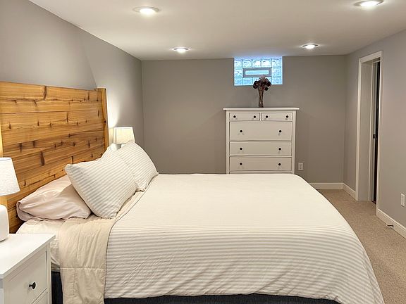 Spacious lower level bedroom featuring a king sized bed and a tempur-pedic mattress for the best night of sleep! Door to bathroom is on the right side.