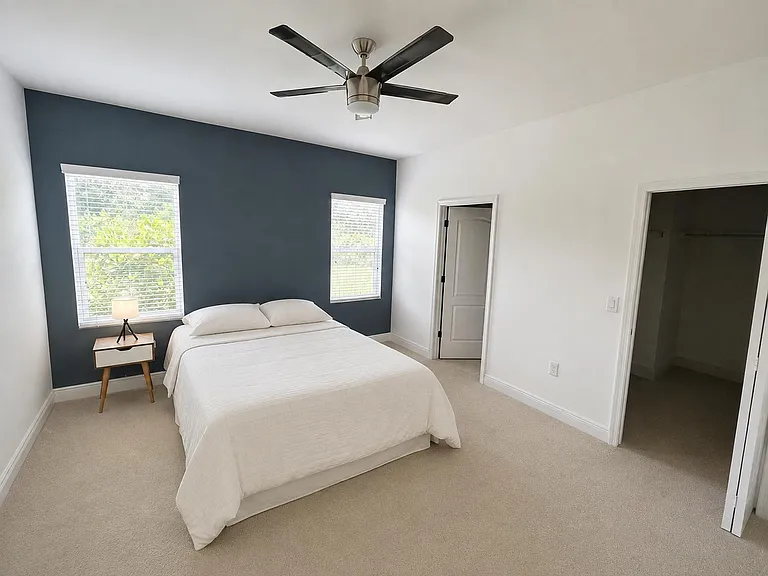 Spacious bedroom with two windows, ceiling fan, soft carpeting, and a large closet for convenient storage.