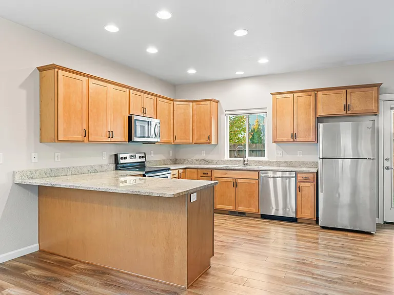 Kitchen with granite countertops, stainless steel appliances & cherry wood cabinets