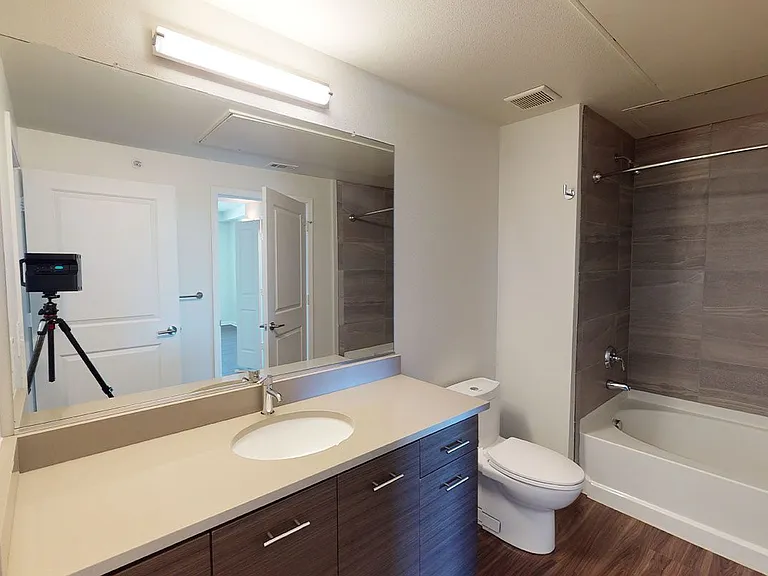 Apartment bathroom with large soaking tub, wood-style flooring.