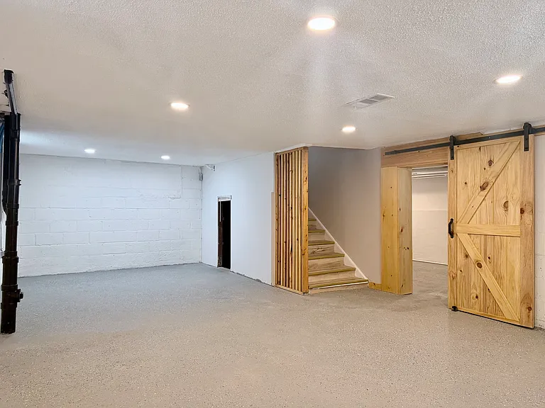 Spacious basement with durable epoxy flooring, high ceilings, barn door access, and excellent potential for recreation or storage.