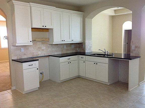 Tumbled marble kitchen backsplash. Stainless steel kitchen appliances and side by side refrigerator 