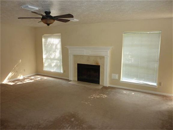 Den with gas log fireplace and ceiling fan